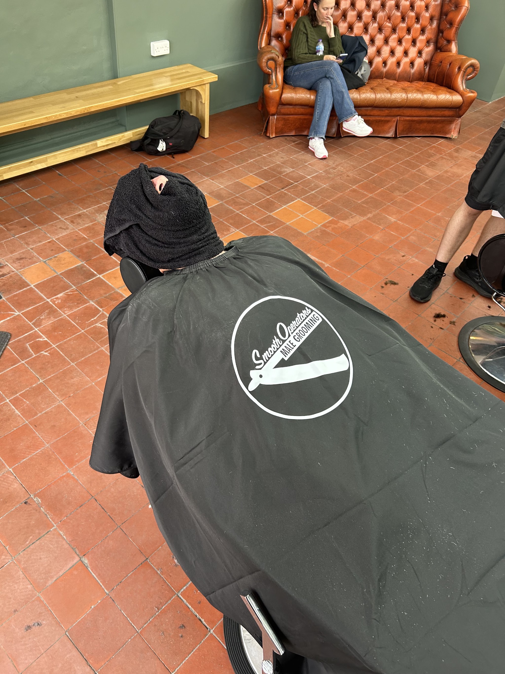 A client in a Smooth Operators cape, with the Chesterfield and bench behind